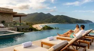 Casal relaxando à beira da piscina com vista para o mar e montanhas em Florianópolis.