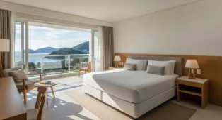Quarto moderno com cama de casal, vista para o mar e decoração clara em Florianópolis.