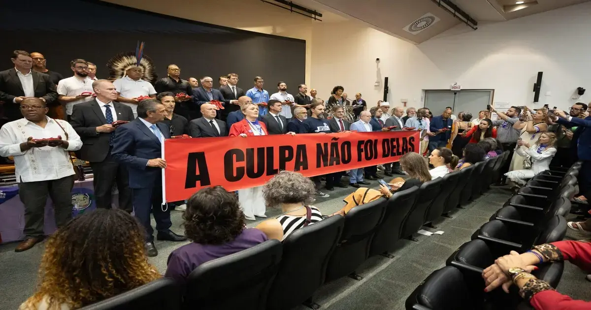 Assembléia Legislativa promove ato contra feminicídio em SC Grupo de pessoas segurando uma faixa vermelha com os dizeres