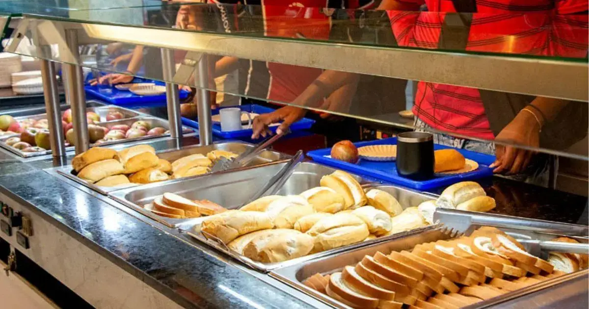 Serviço de café da manhã com diferentes tipos de pães, frutas e bebidas em um buffet.