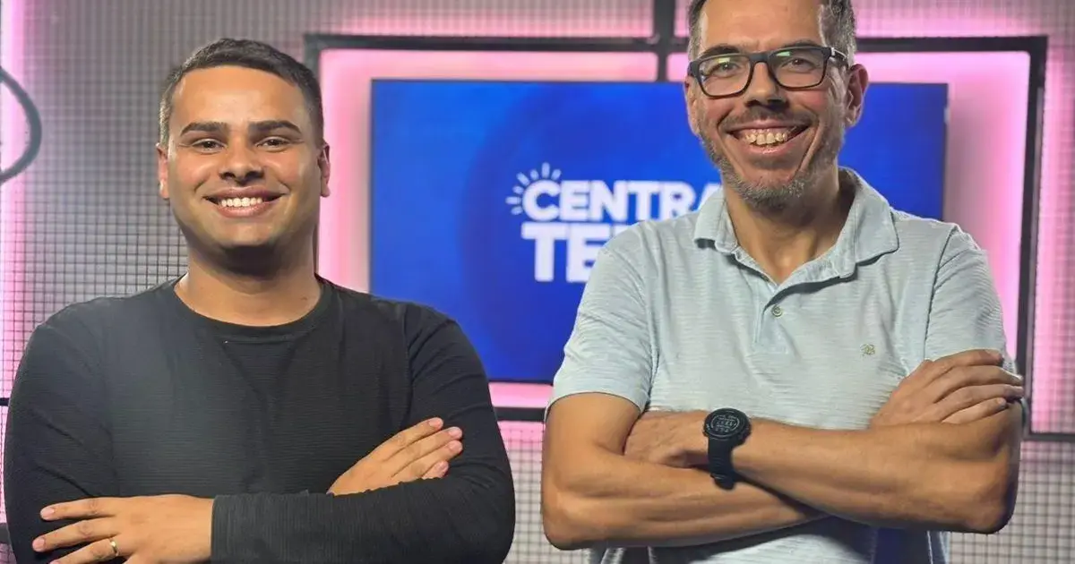 Duas pessoas sorrindo em frente a um fundo com as palavras 