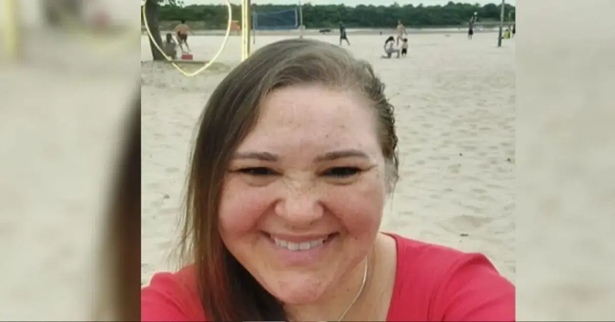 Corretora luciani estivalet freitas encontrada morta em florianópolis Pessoa sorrindo em uma praia com areia clara, ao fundo, outras pessoas brincando e praticando atividades.