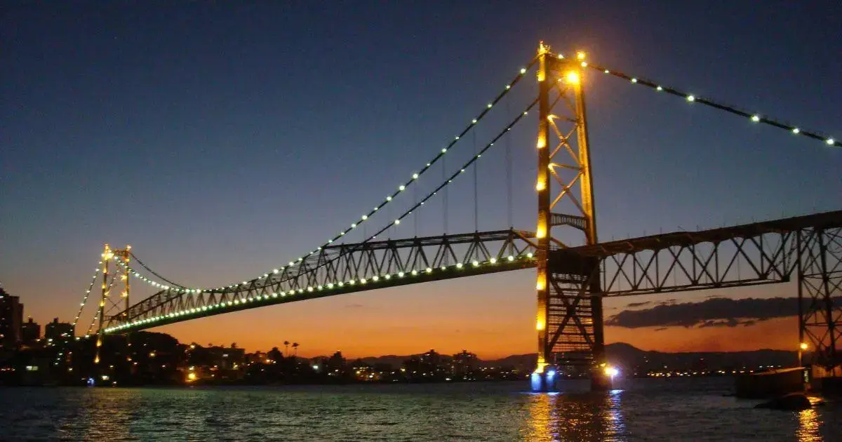 Custo de Vida em Florianópolis em 2026 Ponte iluminada à noite, com céu gradualmente escurecendo e reflexos na água.