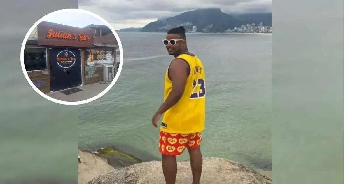 Dono de bar na Lagoa da Conceição preso por estupro de vulnerável Homem de costas, usando camiseta amarelo com número 23 e shorts coloridos, posando em rochas à beira-mar.