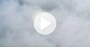 Fenômeno óptico de um arco-íris redondo visível entre nuvens, com um botão de reprodução no centro.