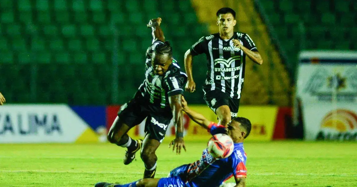 Jogadores em campo durante uma partida de futebol, com um atleta caindo após um lance.