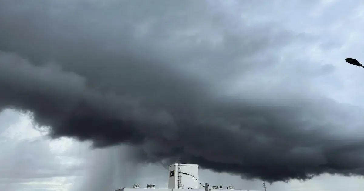 Nuvens escuras e densas em um céu nublado, com um prédio visível na parte inferior da imagem.