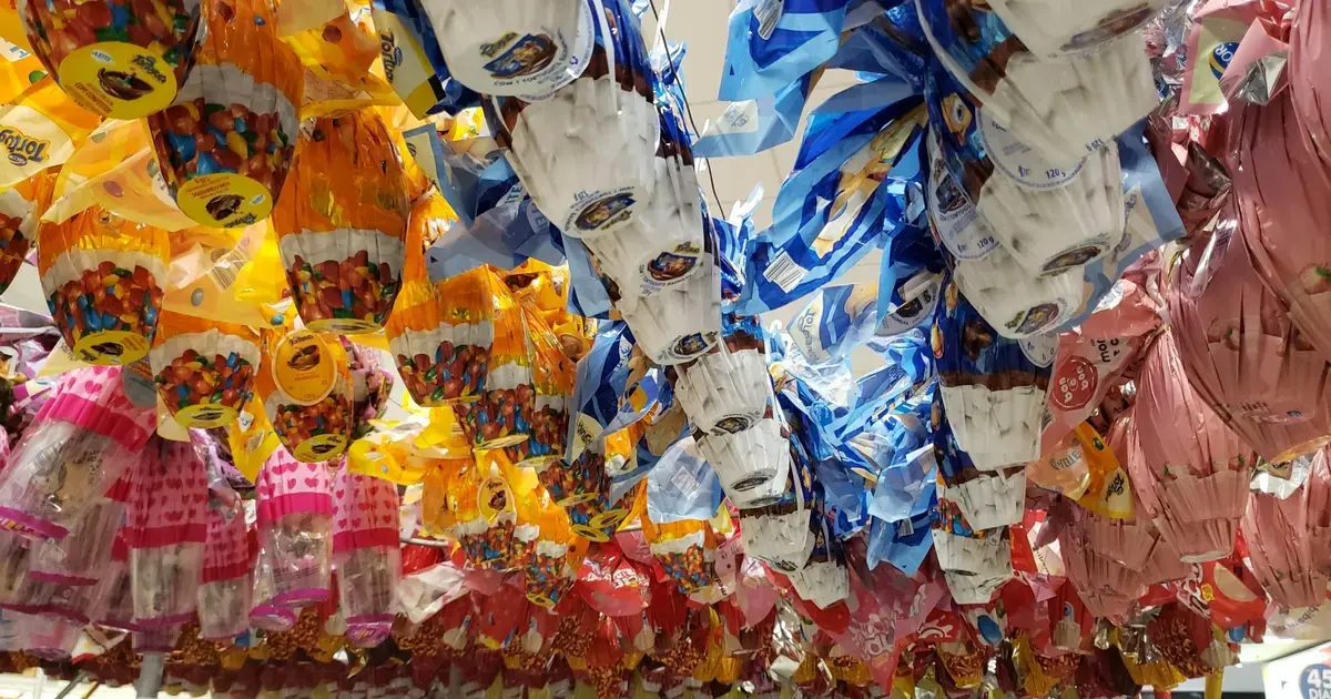 Embalagens coloridas de ovos de Páscoa penduradas, exibindo diferentes sabores e marcas.