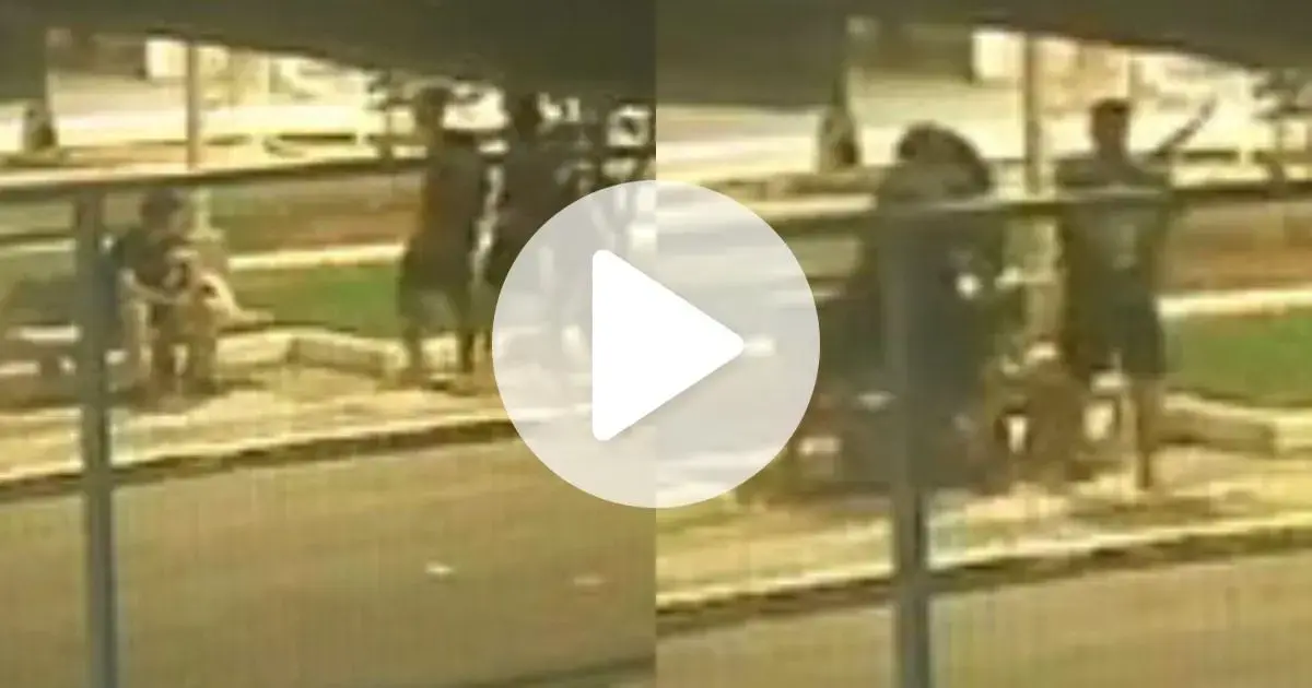 Grupo de homens aborda um pedestre sentado em uma praça, com uma barra visível em mãos.