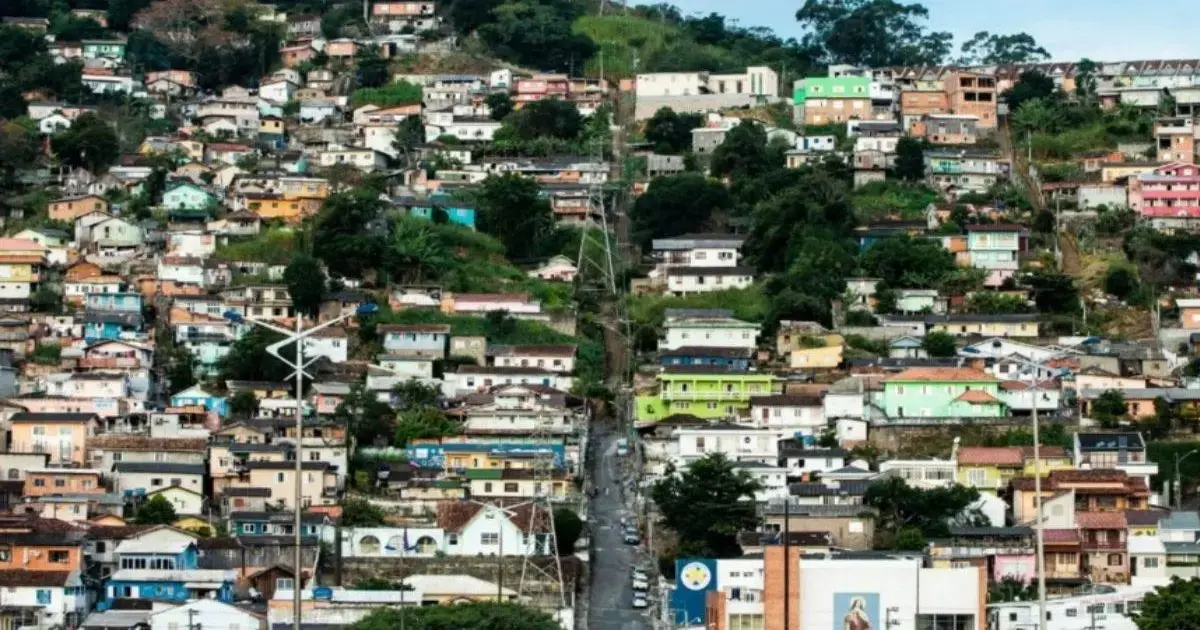 Homem é morto em tribunal do crime no Morro do Mocotó Vista de casas coloridas em um morro, com uma rua central e vegetação ao redor.