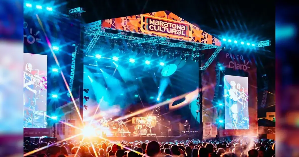 Maratona Cultural de Florianópolis 2026: Programação e Transporte Palco iluminado da Maratona Cultural com pessoas assistindo ao show e projeções em telões.