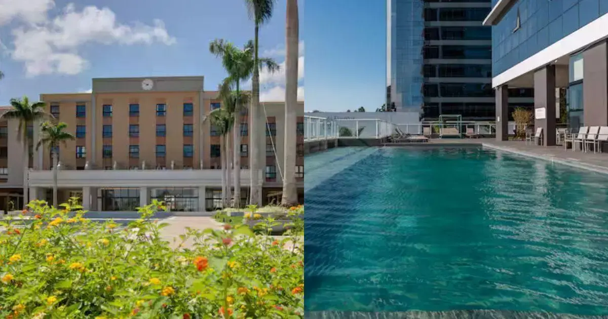 Novo Hotel Hilton em Florianópolis: Projeto até 2028 Edifício com relógio na fachada e piscina ao ar livre, rodeado por palmeiras e flores.