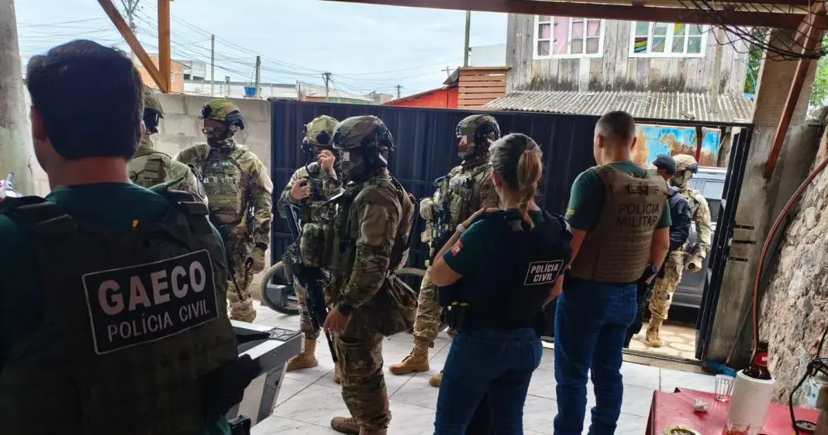 Grupo de policiais civis e militares em operação em uma área urbana, discutindo estratégias.