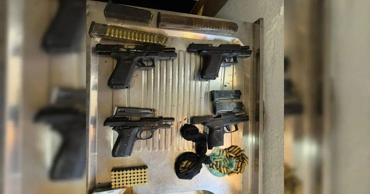 Quatro armas de fogo dispostas em uma superfície metálica, acompanhadas de munições e carregadores.