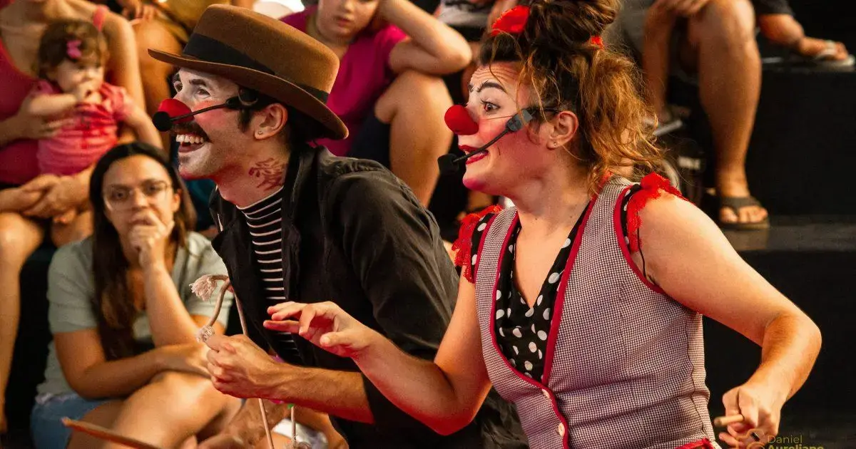 Palhaços se apresentam na 9ª Mostra Traço de Bolso em Florianópolis Artistas de palhaçaria interagindo com a plateia em um espetáculo, com expressão alegre e trajes coloridos.