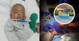 Bebê em leito com tubo de oxigênio, segurando um brinquedo, e equipe médica realizando procedimentos.