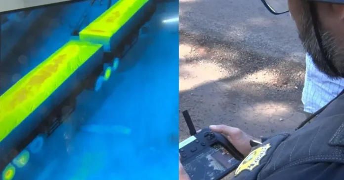 Um drone é controlado à distância, mostrando uma imagem termal de caminhões em uma tela.