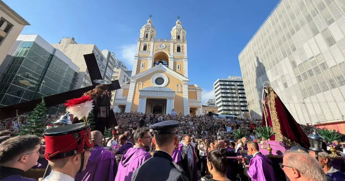 Procissão do Senhor dos Passos reúne milhares de fiéis em Florianópolis Multidão de fiéis reunida em frente a uma igreja enquanto um cortejo religioso acontece, com uma cruz e imagens religiosas.
