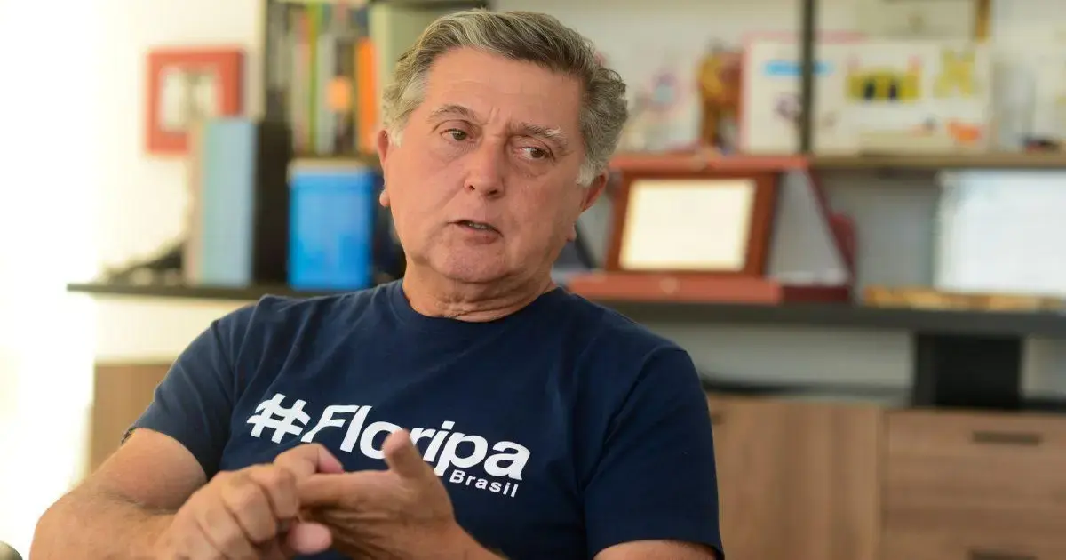 Homem conversando, vestindo camiseta azul com a inscrição 