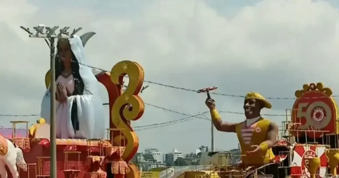 Carros alegóricos de carnaval com uma figura feminina vestindo branco e um homem segurando um objeto em destaque.