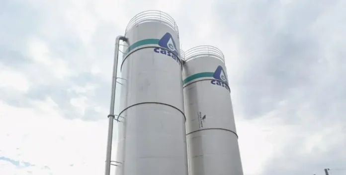 Silos metálicos brancos com a logo da CASAN e céu nublado ao fundo.