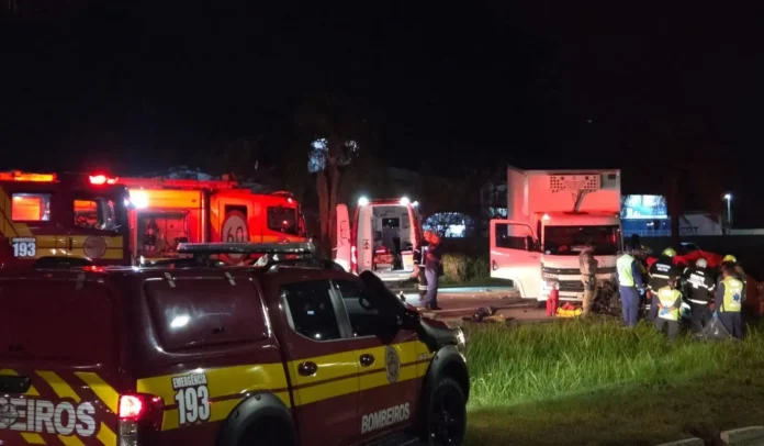 Várias viaturas de bombeiros e ambulâncias em uma cena de acidente à noite, equipes trabalhando no local.
