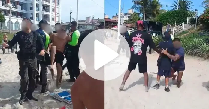 Grupo de pessoas em uma praia, envolvidos em uma situação de confronto, com guardas e ambulantes interagindo.
