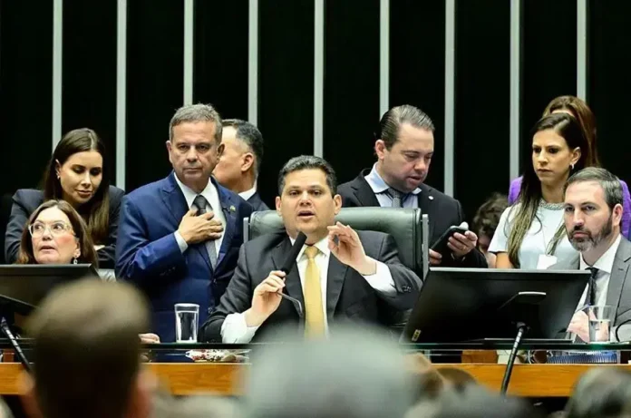 Reunião no plenário, com diversas pessoas em conversação e um parlamentar usando microfone.