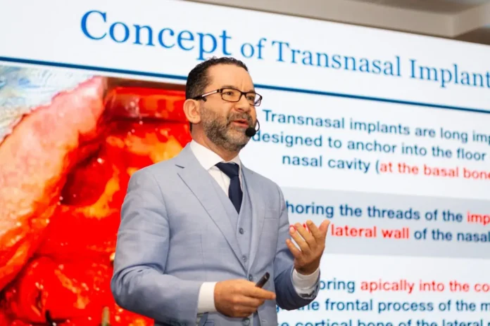 Apresentação sobre implantes transnasais com texto explicativo em fundo. Orador gesticula ao falar.