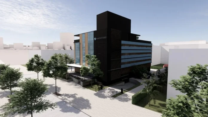 Edifício moderno com várias janelas e faixas coloridas, cercado por árvores e calçadas.