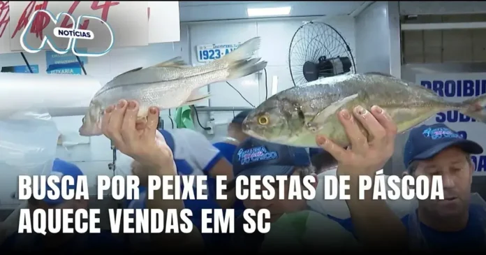 Duas pessoas segurando peixes em mercado, com cartaz sobre vendas aquecidas em SC.