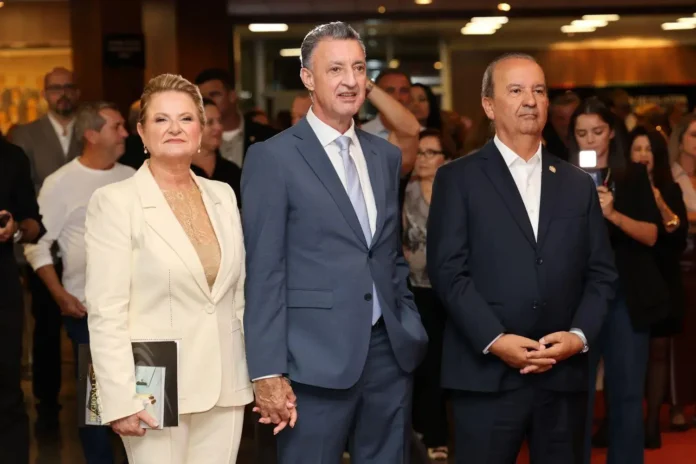 Grupo de pessoas posando em um evento, com destaque para indivíduos vestindo roupas formais.