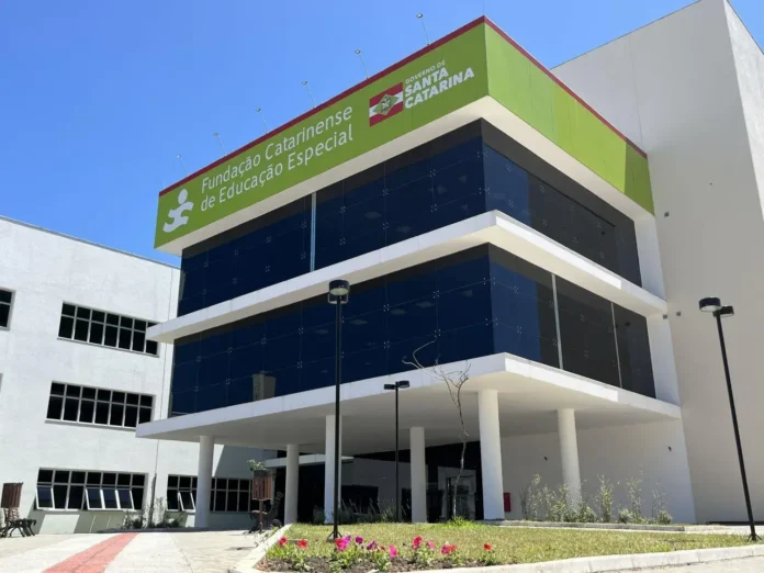 Edifício moderno com fachada de vidro e letreiro da Fundação Catarinense de Educação Especial. céu azul ao fundo.