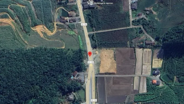 Vista aérea de uma área rural com a rodovia SC-108, cercada por campos e vegetação.