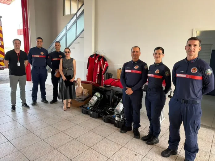 Grupo de bombeiros em uniformes, com equipamentos de salvamento e simuladores de CPR em ambiente interno.