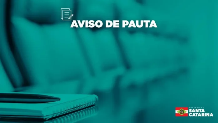 Aviso de pauta em destaque sobre fundo azul, com caneta e caderno em primeiro plano.
