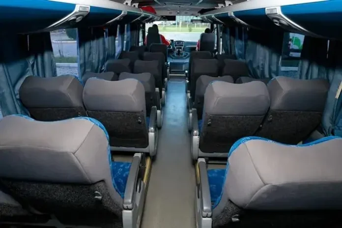 Interior de um ônibus mostrando fileiras de poltronas confortáveis e o espaço entre elas.
