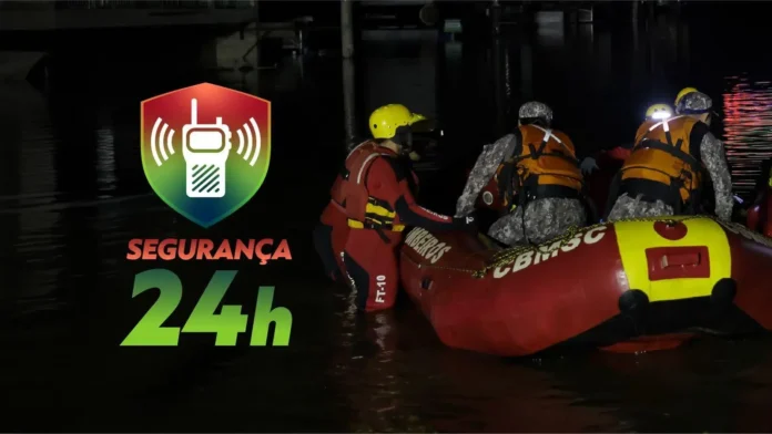 Homens em um barco de resgate em águas escuras, com equipamentos de segurança, durante atividade noturna. Texto: "SEGURANÇA 24h".