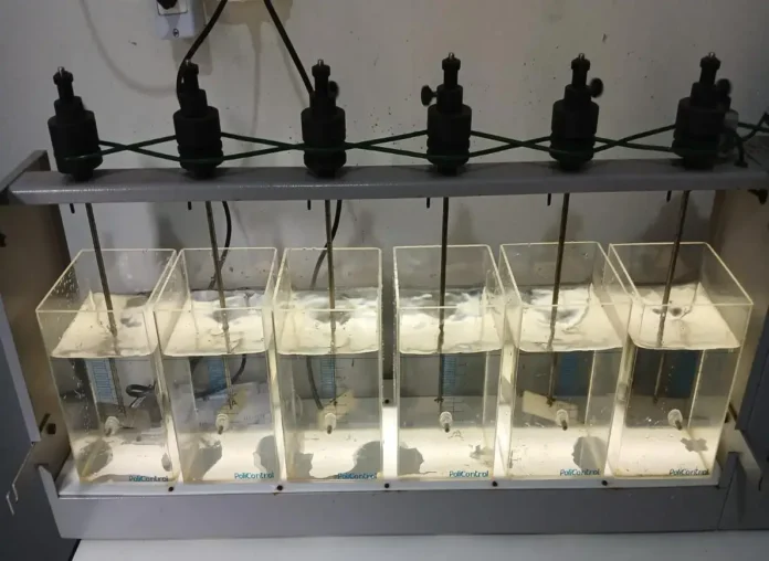 Equipamento de laboratório com seis tanques transparentes contendo água e tubos de medição.