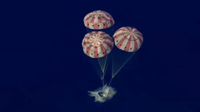 Cápsula espacial pousando no Oceano com três paraquedas abertos.
