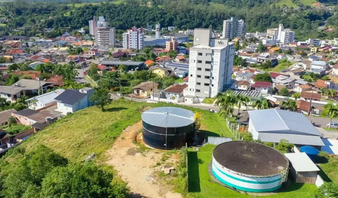 Vista aérea de uma área urbana com tanques de água e diversas construções ao fundo.