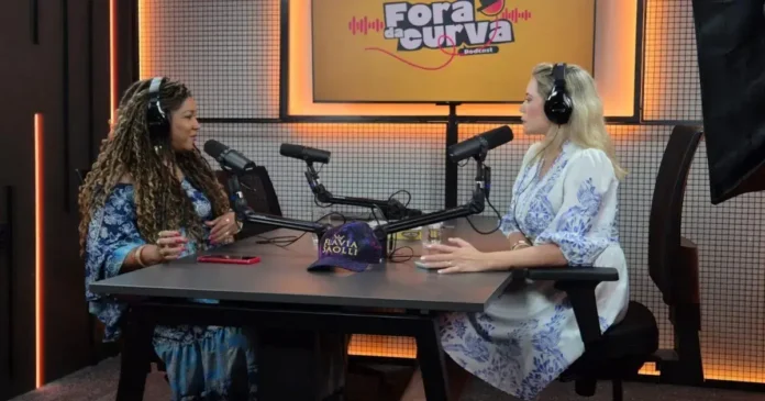Duas pessoas conversando em um estúdio de podcast, com microfones e decoração moderna ao fundo.