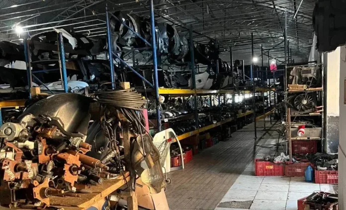 Estante com peças automotivas usadas organizadas em um galpão, incluindo componentes de motor e carcaças.