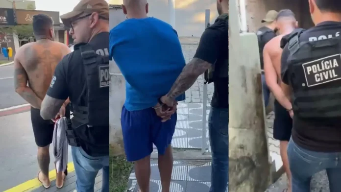 Homens em situação de detenção, cercados por agentes da polícia, caminhando em direção a uma área restrita.