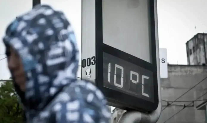 Temperatura de 10°C exibida em um painel digital, com uma pessoa vestindo um capuz ao fundo.