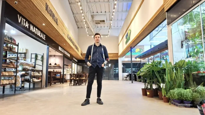 Espaço comercial interno com prateleiras de produtos, mesas e plantas em vasos, e uma pessoa ao centro.