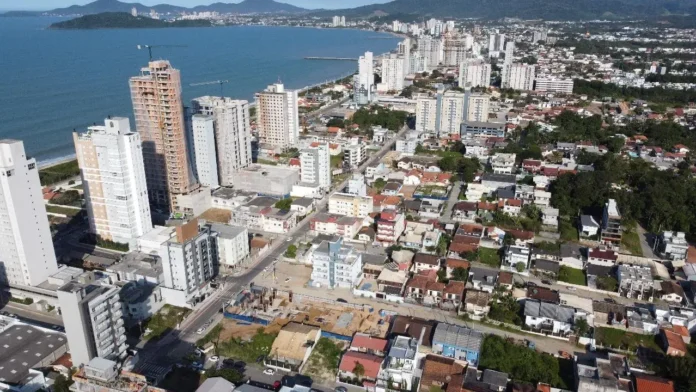 Vista aérea de uma área urbana com prédios e casas, próxima ao mar, em uma cidade costeira.