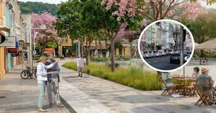 Pessoas caminhando e conversando em uma calçada arborizada, com flores, bicicletas e mesas de café ao fundo.