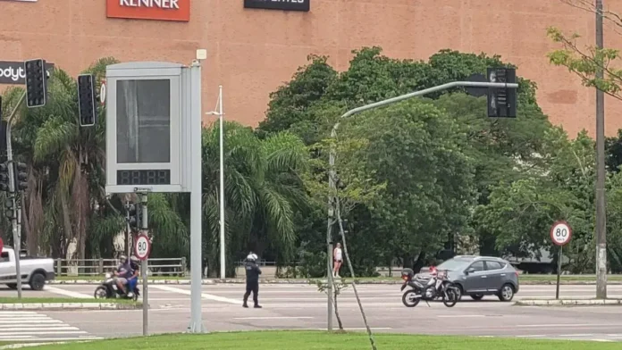 Semáforos, sinalização de limite de velocidade de 80 km/h, e pessoas em um cruzamento com veículos.