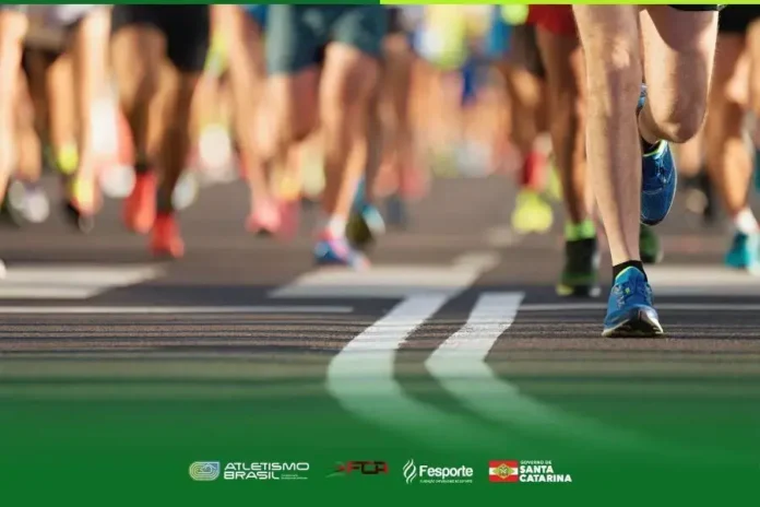 Pessoas correndo em uma pista, com foco nas pernas e pés em movimento. Marcas de piso visíveis.